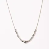 Collar plateado con cadena fina y dije de bolitas plateadas de diferentes tamaños.