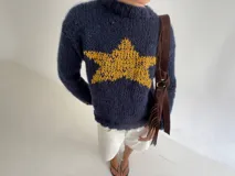Buzo de tejido de punto grueso en color azul marino, con cuello redondo y diseño de estrella grande en color amarillo en el centro del pecho.