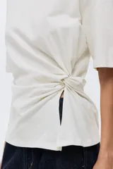 Remera de punto suave de algodón con cuello redondo y detalle de nudo girado en un lateral.