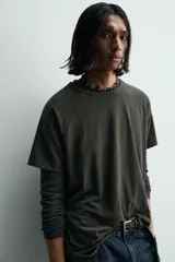 Camiseta relaxed fit color gris oscuro, confeccionada en tejido ligero de algodón con elasticidad. Presenta cuello redondo y manga ranglán corta.