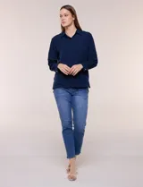 Camisa blanca de corte clásico y caída fluida, con cuello camisero tradicional, abotonadura frontal oculta y mangas largas con puños anchos.