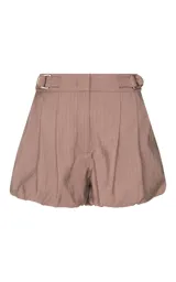Short balloon Roxana de la marca Le Lis Blanc, color tostado, con cintura ancha, hebillas laterales metálicas ajustables, pliegues delanteros y cierre frontal de cremallera.