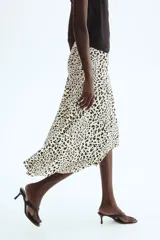 Pollera midi asimétrica de viscosa, con estampado animal print de leopardo, tiro alto y elástico oculto en la cintura. Presenta costura diagonal en las caderas y caída al bies con bajo irregular.