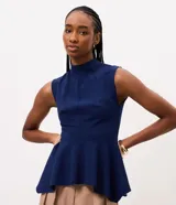Blusa azul marino sin mangas de la marca Cortelle, con cuello alto, recortes estructurales y dobladillo estilo peplum asimétrico.