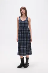 Vestido midi sin mangas confeccionado en algodón con estampado de cuadros en tonos azul y negro. Presenta un diseño holgado con cuello redondo y cierre posterior.