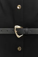 Chaleco negro de vestir, sin mangas, con cuello redondo y cierre frontal de botones metálicos dorados. Incluye dos bolsillos frontales con solapa y un cinturón negro a tono con hebilla metálica dorada.