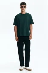 Remera en punto de algodón verde oscuro, con cuello redondo ribeteado, hombros caídos, mangas cortas y bajo recto de corte relajado.