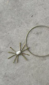 Gargantilla dorada con dije en forma de sol con perla barroca en el centro.