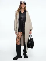 Kimono largo de tejido de punto en color beige, con diseño de sisa caída y mangas abullonadas que aportan volumen. Presenta una silueta relajada y abierta al frente.