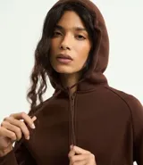 Saco femenino de algodón con capucha ajustable, mangas largas, cierre frontal con cremallera y bolsillos laterales.