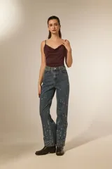 Pantalón jean azul de corte recto y calce alto, con bolsillos y detalles de strass.