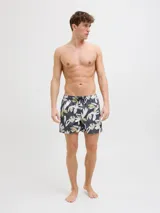Short de baño con estampado floral abstracto en tonos verdes, beige y blancos sobre base gris oscuro. Presenta cintura elástica con cordón ajustable y bolsillos laterales.