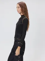 Polera de manga larga confeccionada en tela rib color bordó, con cuello alto y hombreras. Presenta costuras a la vista con pespuntes en hilo de color contrastante en el cuello, puños, hombros y ruedo.