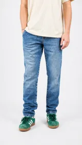 Pantalón de jean azul con lavado clásico, corte recto y cierre frontal con botones.