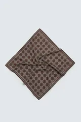 Pañuelo cuadrado de algodón, color marrón oscuro, con estampado geométrico repetitivo en color beige claro y bordes definidos por líneas finas blancas y moradas.
