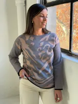 Sweater de punto con diseño estampado abstracto en tonos gris y beige, cuello redondo y terminaciones en color negro.