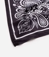 Pañuelo cuadrado de poliéster con estampa paisley en tonos oscuros y blancos, de caída ligera y diseño versátil.