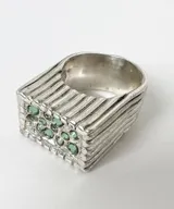 Anillo tipo sello de plata 950 con diseño de líneas horizontales y cristales verdes incrustados.
