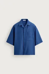 Camisa de manga corta azul con corte boxy fit, cuello bowling y un bolsillo de parche en el pecho.