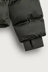 Cazadora puffer acolchada de corte relaxed fit color negro, confeccionada en tejido técnico repelente al agua. Cuenta con cuello subido, capucha ajustable con elásticos y cierre frontal con cremallera. Tiene bolsillos de vivo en la cadera, bolsillo interior y mangas largas con puños elásticos ajustables con abertura para el dedo pulgar.