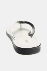 Sandalia plana de piel en color blanco, con diseño de dedo y detalle de aplique metálico. Presenta una suela plana en color negro.