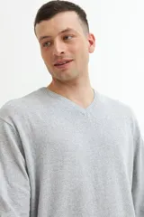 Sweater verde oscuro de tejido de punto, con escote en V y mangas largas.