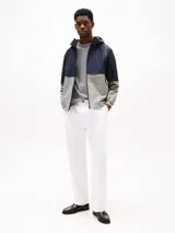 Campera deportiva Tommy Hilfiger para hombre, confeccionada en nylon, con diseño de bloques de colores azul marino y gris, capucha ajustable, cierre frontal con cremallera y logo bordado en el pecho.