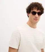 Remera de corte regular confeccionada en algodón, con cuello redondo y mangas cortas. Presenta una textura de rayas horizontales trabajadas en relieve sobre toda la prenda.