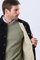 Campera de pana negra con forro interior de corderito, cuello camisero, cierre frontal con botones y bolsillos frontales con solapa.
