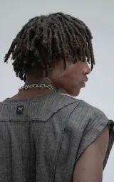 Sudadera sin mangas de cuello redondo, color gris oscuro, confeccionada en tejido de hilo liviano con textura acanalada y recortes superpuestos que crean un efecto de relieve asimétrico.