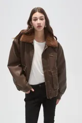 Campera de eco-cuero color marrón con cuello de piel sintética, cierre frontal, bolsillos frontales con solapa y puños y cintura elásticos.