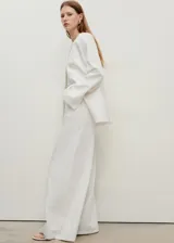 Pantalón de jean estilo wideleg, de tiro alto y corte largo, con diseño de cinco bolsillos, trabillas para cinturón y cierre frontal con cremallera y botón.