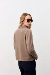Cardigan de punto color taupe con cuello polo y cierre frontal de botones. Presenta mangas largas con puños ajustados y un corte recto a la altura de la cintura.