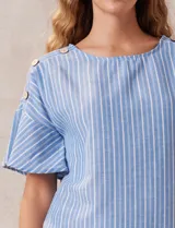 Blusa de mangas cortas amplias con aplique de botones en los hombros. Diseño a rayas verticales celestes y blancas.