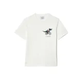 Remera de algodón blanca de corte clásico, con cuello redondo y manga corta. Presenta un pequeño estampado en el pecho que muestra al icónico cocodrilo de Lacoste vestido con ropa deportiva y montando una bicicleta, junto con los logotipos de Lacoste y Netflix.