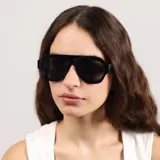 Lentes de sol con armazón de acetato negro y diseño de puente plano, estilo aviador moderno con cristales oscuros.