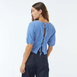 Blusa corta a cuadros azules y blancos, con cuello redondo y mangas cortas abullonadas.