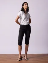 Pantalón capri negro de algodón elastizado. Pretina con pasadores, botón y cierre. Delantera con bolsillos. Trasera con bolsillos simulados.