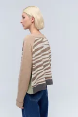 Cardigan de tejido de punto color beige con estampado de cebra en el cuerpo y mangas largas.