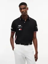 Chomba negra de algodón elástico con cuello polo, cartera de dos botones y mangas cortas. Presenta detalles de ribetes con diseño Global Stripe en el cuello y los puños, además de los logotipos de Tommy Hilfiger, TH x Cadillac Formula 1 Team, Pirelli y el número 11 en las mangas y el pecho.