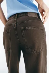Jeans de tiro medio y corte recto, color marrón chocolate. Presenta un diseño de cinco bolsillos y detalles laterales con tejido de crochet a tono a lo largo de las piernas.