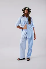 Pantalón celeste a rayas verticales blancas, de corte palazzo y cintura alta con elástico.