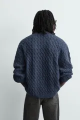 Jersey de punto con diseño de trenzas, cuello redondo y manga larga. Presenta un ajuste oversized y acabados en rib en puños y ruedo.