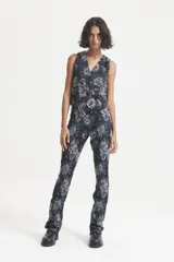 Pantalón negro con estampado floral en tonos grises y azules. Diseño de tiro alto con cierre invisible en la bota y recortes verticales.