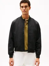Campera bomber Tommy Hilfiger de color negro, confeccionada con tejido técnico de nailon reciclado y poliamida resistente al viento y la humedad ligera. Presenta diseño de corte clásico con cierre frontal de cremallera, cuello, puños y dobladillo en rib elástico, y dos bolsillos laterales de ojal. Incluye el logo monotipo bordado discretamente en el pecho.