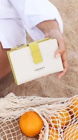 Billetera mediana marca Lincoln's, color beige con detalles en verde lima. Cuenta con cierre de presilla, compartimentos para tarjetas, espacio para billetes y monedero con cierre.