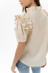 Camisa celeste de lino con cuello mao y mangas cortas abullonadas con volados. Cierre frontal con botones.