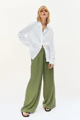 Pantalón de tiro alto con pernera ancha, confeccionado en tejido de lino. Presenta cintura elástica con cordón ajustable, pinzas delanteras, bolsillos laterales y bolsillos de plastrón en la parte posterior.