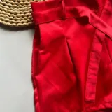 Short rojo de satén con bolsillos delanteros, pasacintos y cinturón de la misma tela.