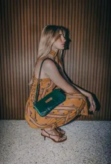 Cartera bandolera pequeña de cuero verde esmeralda con correa fina al tono.